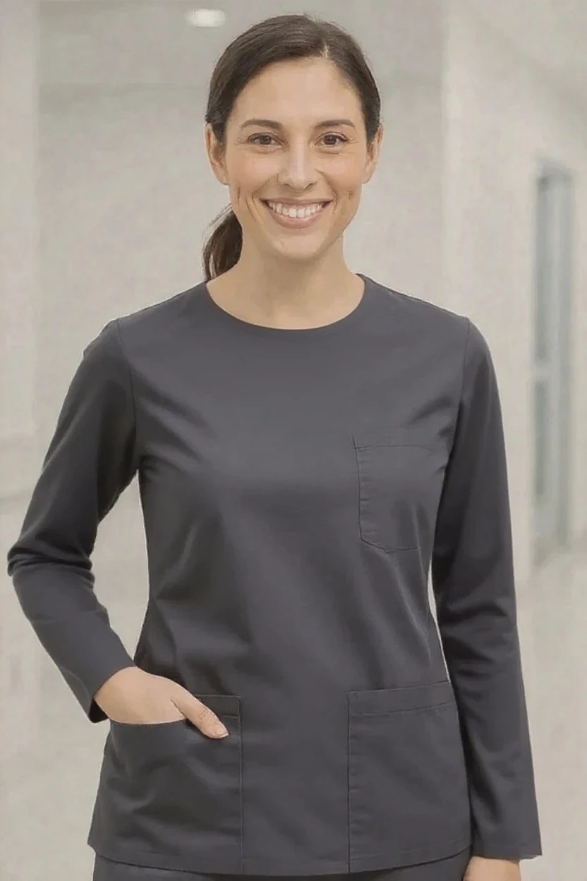 Woman wearing a dark gray scrub top with a neutral background